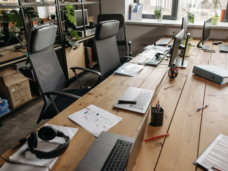 Espace de travail partagé en entreprise avec ordinateurs, écrans et documents sur un long bureau